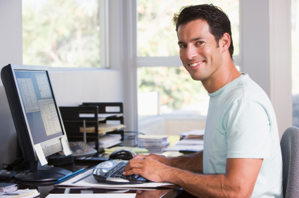 Man in home office using computer and smiling